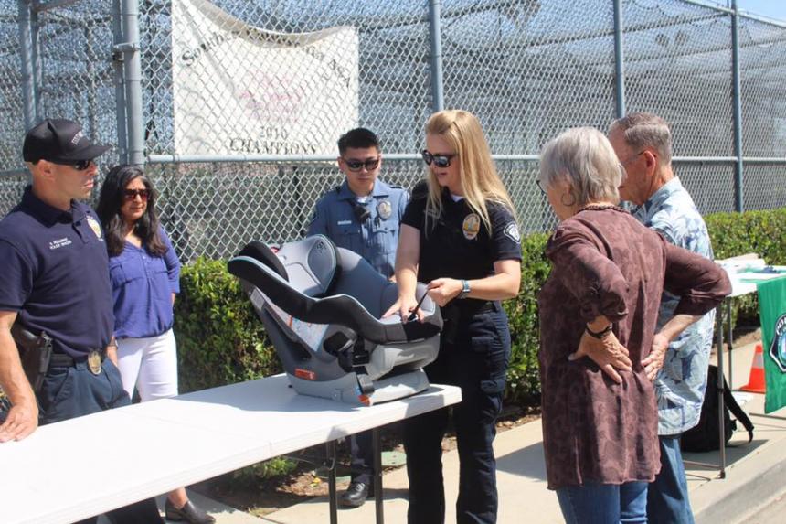 Irvine Police officers go over infant car seat safety tips with new grandparents while Councilwoman Farrah Khan watches.